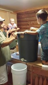 Junior Beekeeper spins the honey while his sister watches